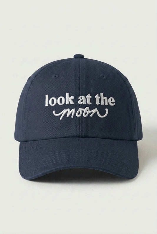Navy blue cap with 'look at the moon' text on a light gray background